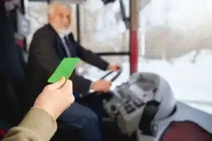Pessoa apresentando um cartão verde ao motorista, enquanto entra em um ônibus